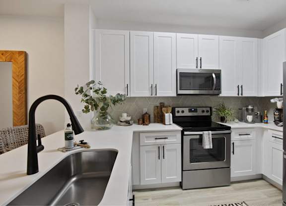 a white kitchen with stainless steel appliances and white cabinets