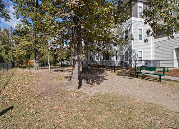 a park with a bench and trees in front of a building