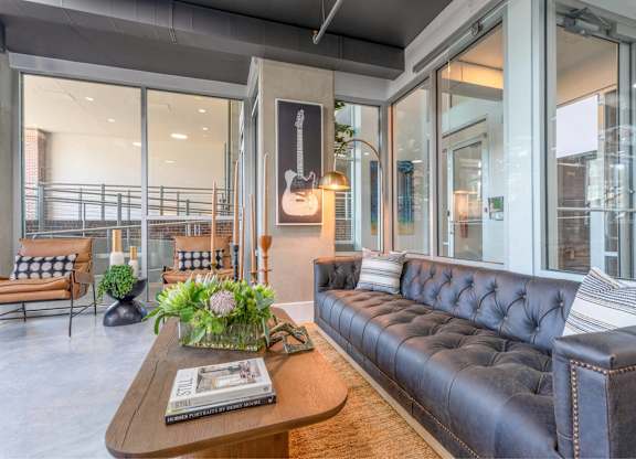 A living room with a black leather couch and a wooden coffee table.