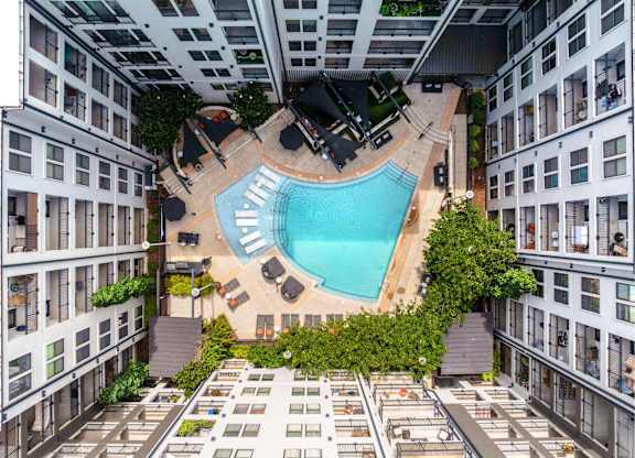 A swimming pool is surrounded by lounge chairs and umbrellas.
