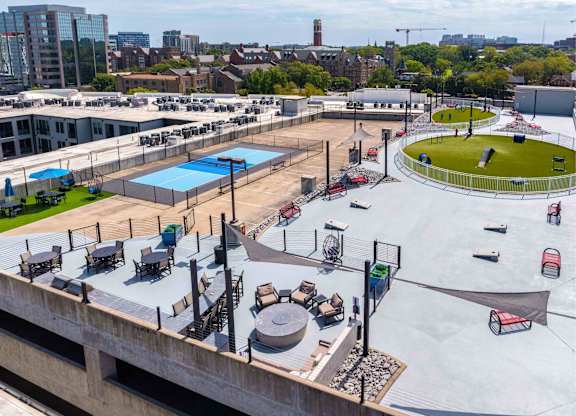 A rooftop with a pool, loungers, and a green space.