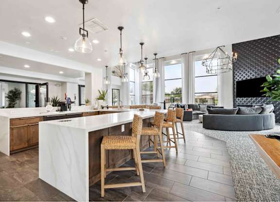 Clubhouse kitchen with a large center island next to a living room with a couch and a fireplace