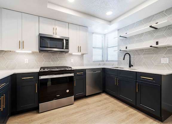 a kitchen with blue and white cabinets and stainless steel appliances