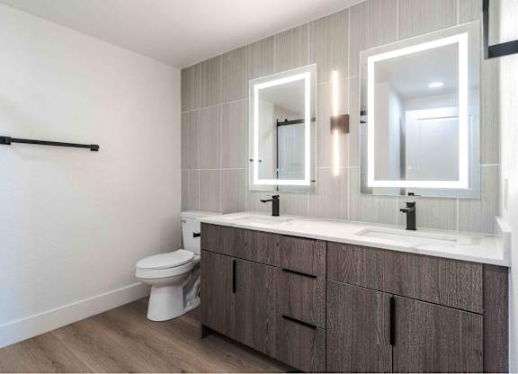 A bathroom with a toilet, sink, and mirrors.