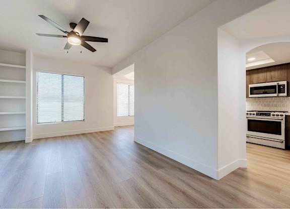 an empty living room with a ceiling fan