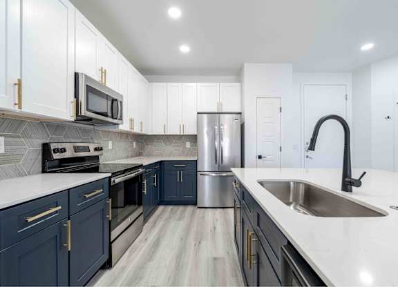 a kitchen with blue and white cabinets and stainless steel appliances