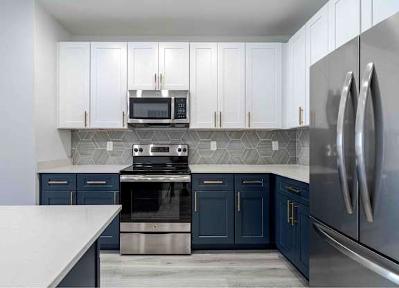 a kitchen with blue and white cabinets and stainless steel appliances
