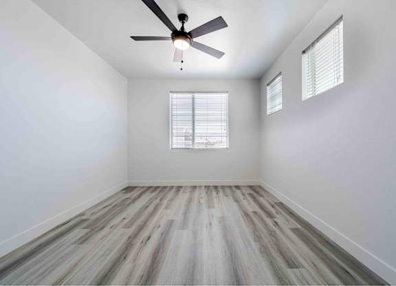 an empty room with wood floors and a ceiling fan