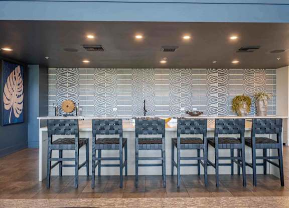 a large table with chairs in front of a wall with a geometric pattern