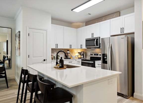 A kitchen with white cabinets and a white island.