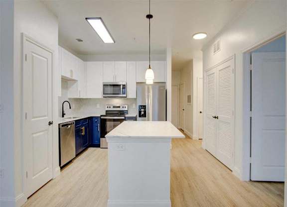 A kitchen with white cabinets and a white island.