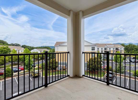 A balcony overlooks a parking lot and buildings.
