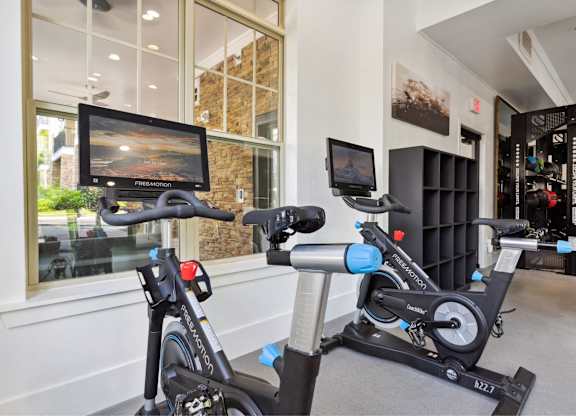 A stationary bike and a treadmill are in a room with a TV.