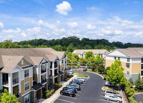 A sunny day at a residential complex with cars parked in the lot.