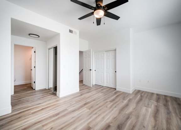 A room with a ceiling fan and wooden flooring.