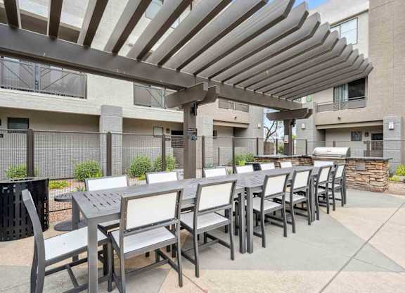 A patio with a table and chairs under a pergola.