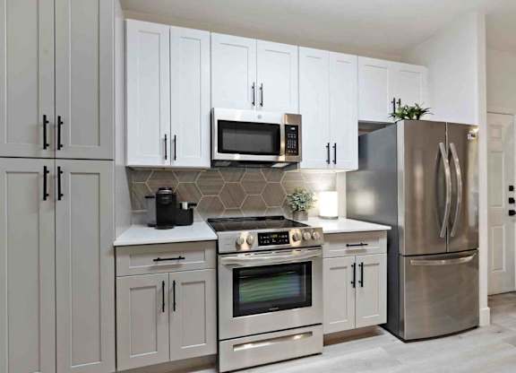 A modern kitchen with stainless steel appliances and white cabinets.