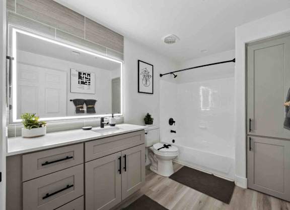 A bathroom with a white countertop and grey cabinets.