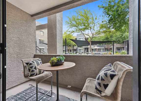 A patio with a table and two chairs with a view of apartment buildings.