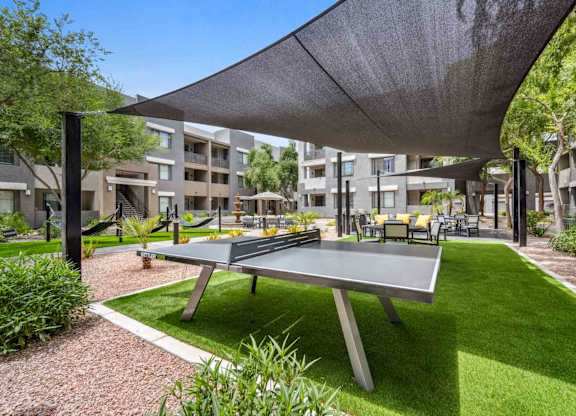 A ping pong table is in the middle of a grassy area.