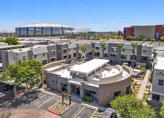 A modern building with a circular courtyard in the foreground and a large stadium in the background.