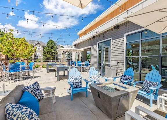 a patio with blue chairs and a fire pit