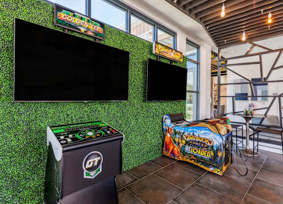 a game room with green astroturf and flat screen televisions