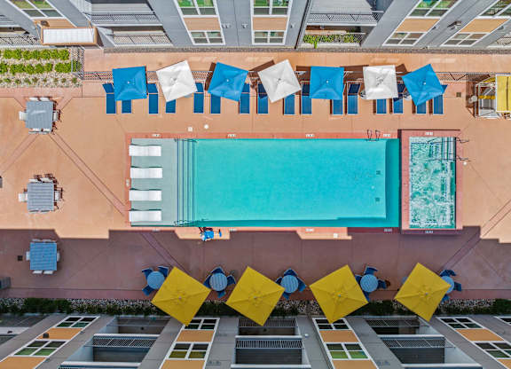 a birds eye view of a building with a pool and blue and yellow tables and chairs