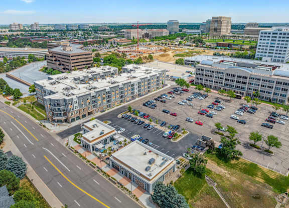an aerial view of a large parking lot with several buildings in the background
