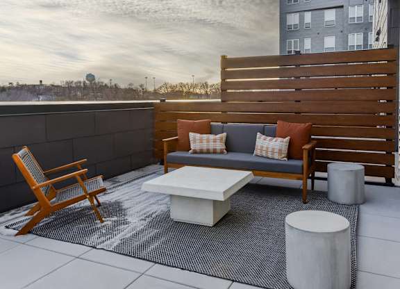 A wooden chair and a white table are on a patio.