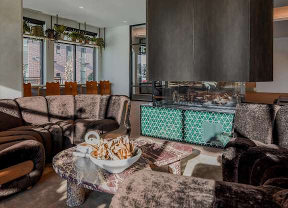 A bowl of chips sits on a coffee table in a room with brown velvet chairs.