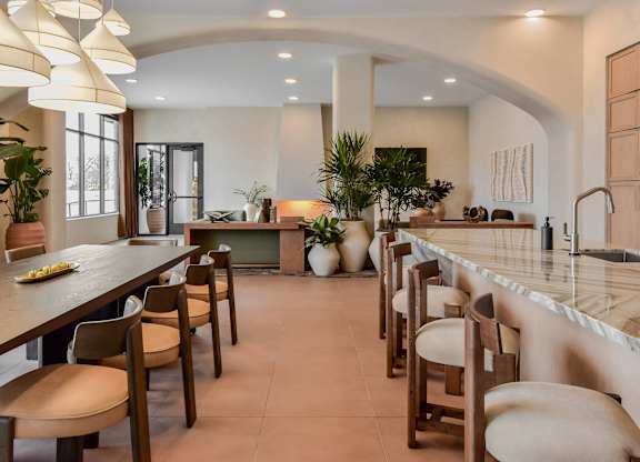 A kitchen with a long table and chairs.