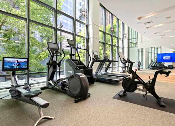 A gym with exercise equipment and a TV screen.