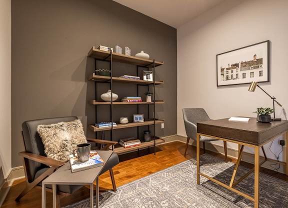 A room with a chair, a desk, and a shelf with books and decorative items.