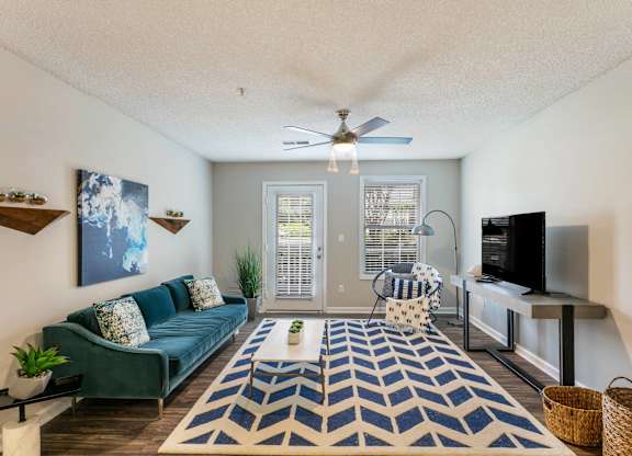 A living room with a blue couch and a rug.