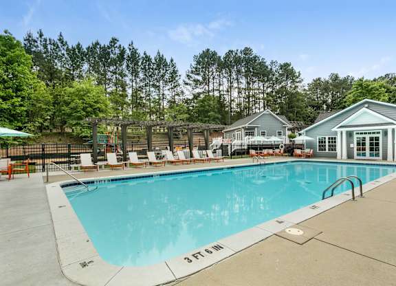 Pool next to line of tall trees at Aqua Sandy Springs apartments for rent in Sandy Springs, GA.