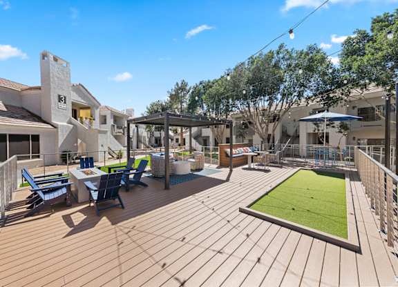 A wooden deck with a green lawn and blue chairs.