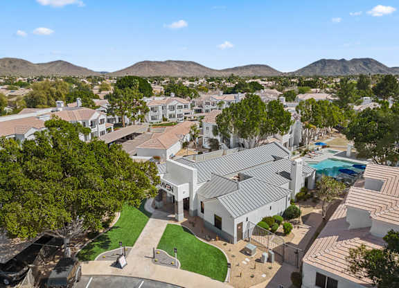 A large white building with a pool in the foreground and a mountain range in the background.