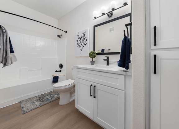 A white bathroom with a toilet, sink, and mirror.