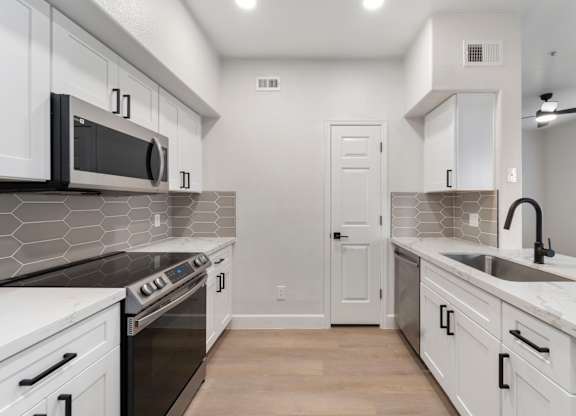 A modern kitchen with white cabinets and a black countertop.
