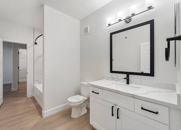 A bathroom with a toilet, sink, and mirror.