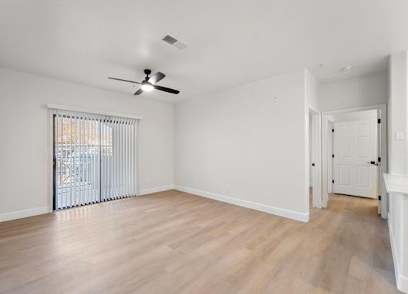 A room with a ceiling fan and sliding glass doors.