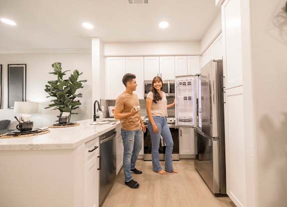 A man and woman are standing in a modern kitchen.