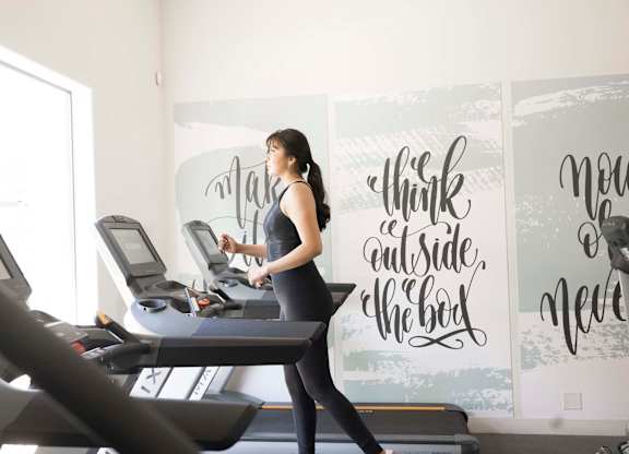 A woman is running on a treadmill in a gym.