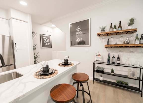 A kitchen with a white marble countertop and a wooden stool.