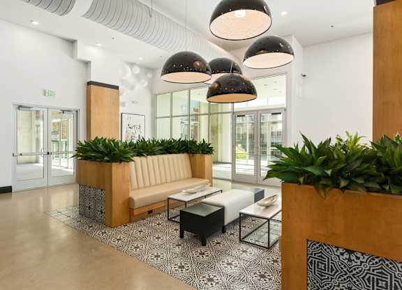 A modern waiting area with a bench, plants, and hanging lights.
