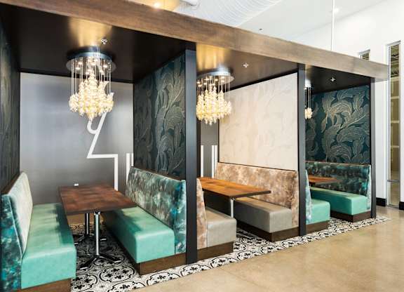 A modern dining area with a wooden table and green upholstered chairs.