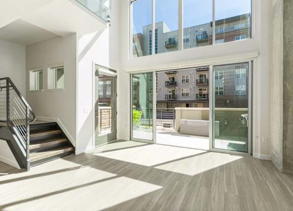 A modern interior with a staircase and glass doors leading to a balcony.