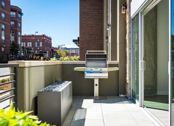 A modern outdoor kitchen area with a grill and sink.