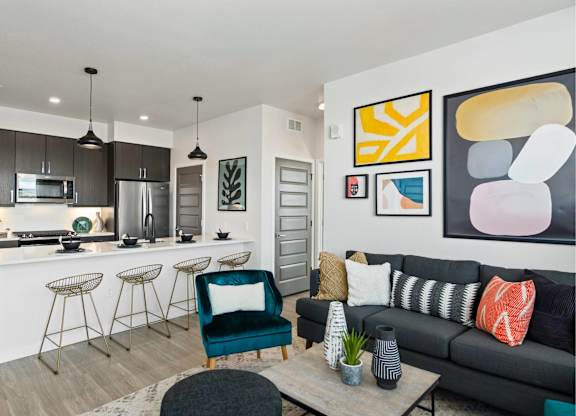 A modern kitchen with a bar and a living room with a couch.